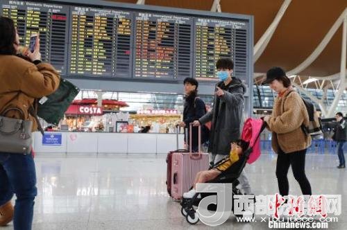 旅客帶著孩子前往辦票柜臺辦理登機手續(xù)?！∫罅⑶?攝