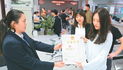 河北省承德市網(wǎng)絡(luò)代購經(jīng)營者陳晨(右)從工作人員手中接過帶有統(tǒng)一社會信用代碼的營業(yè)執(zhí)照。 劉環(huán)宇攝(人民圖片)