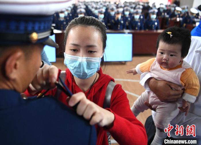 新消防員楊振的妻子彭莉與女兒現(xiàn)場見證丈夫加入“火焰藍”的神圣時刻?！⒅铱?攝